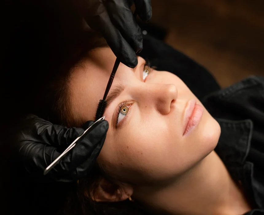 high-angle-female-clinician-doing-eyebrow-treatment-female-customer